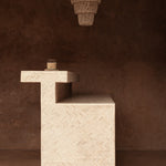 Textured stone pedestal with a hanging shell chandelier light on a brown background