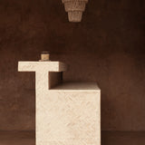 Textured stone pedestal with a hanging shell chandelier light on a brown background