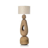 Floor standard lamp with an earthy textured base and linen shade on a white background