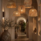Decorative hallway with hanging wicker rattan light shades and potted plants.