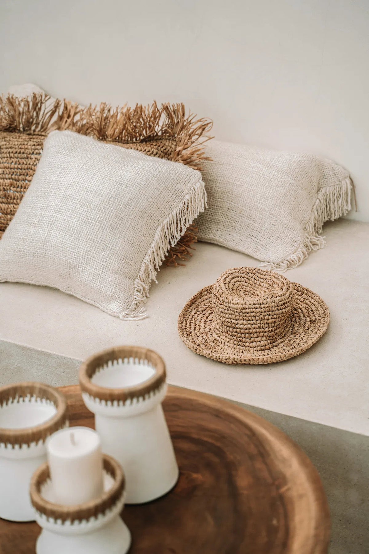 Decorative setting with woven raffia, candles, and cushions on a neutral sofa