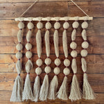 Textile wall hanging with tassels on a wooden wall