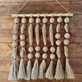 Textile wall hanging with tassels on a wooden wall