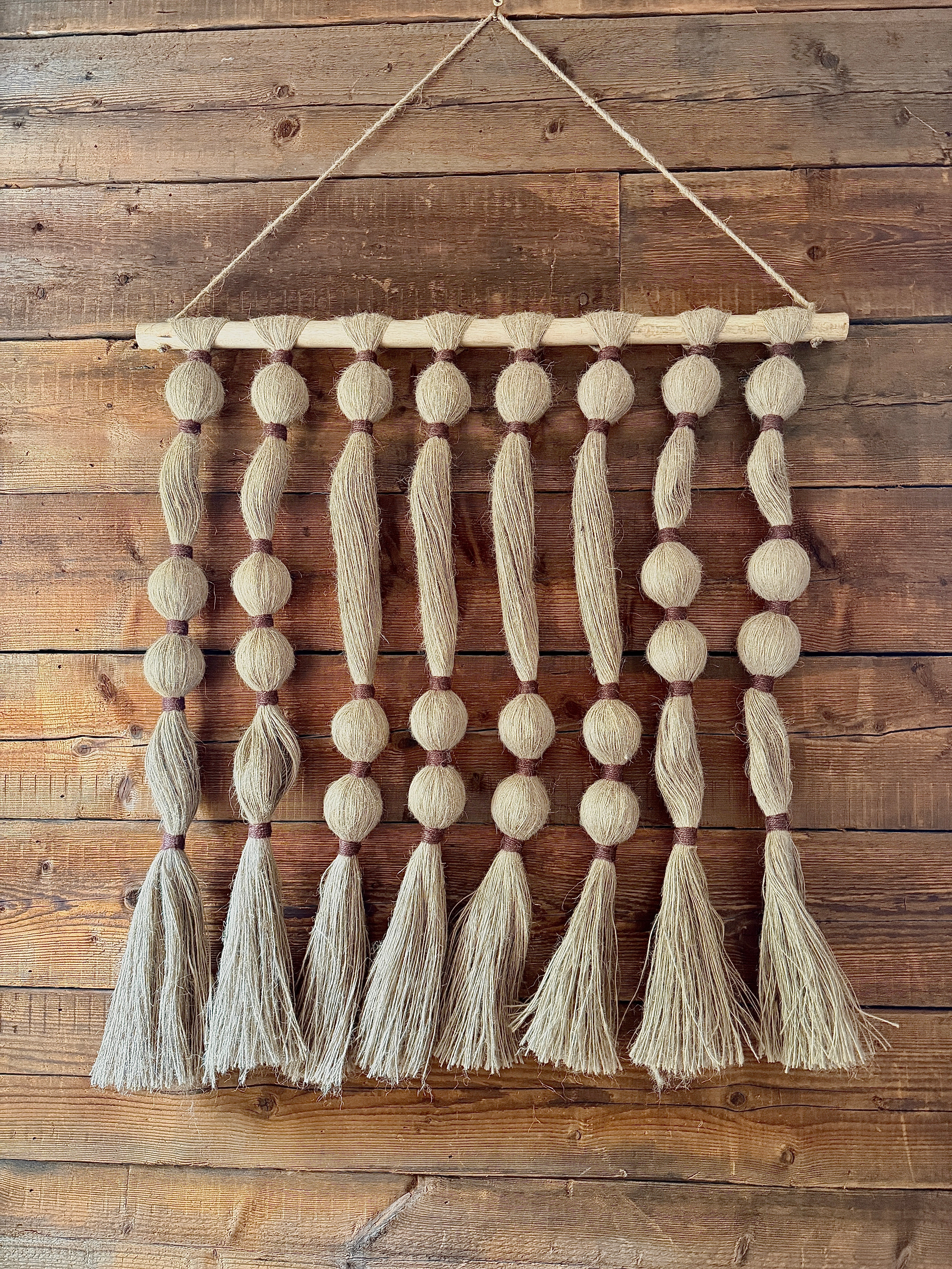 Textile wall hanging with tassels on a wooden wall