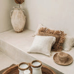 lime wash plastered room with raffia and wood accessories and cream cushions