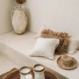 lime wash plastered room with raffia and wood accessories and cream cushions