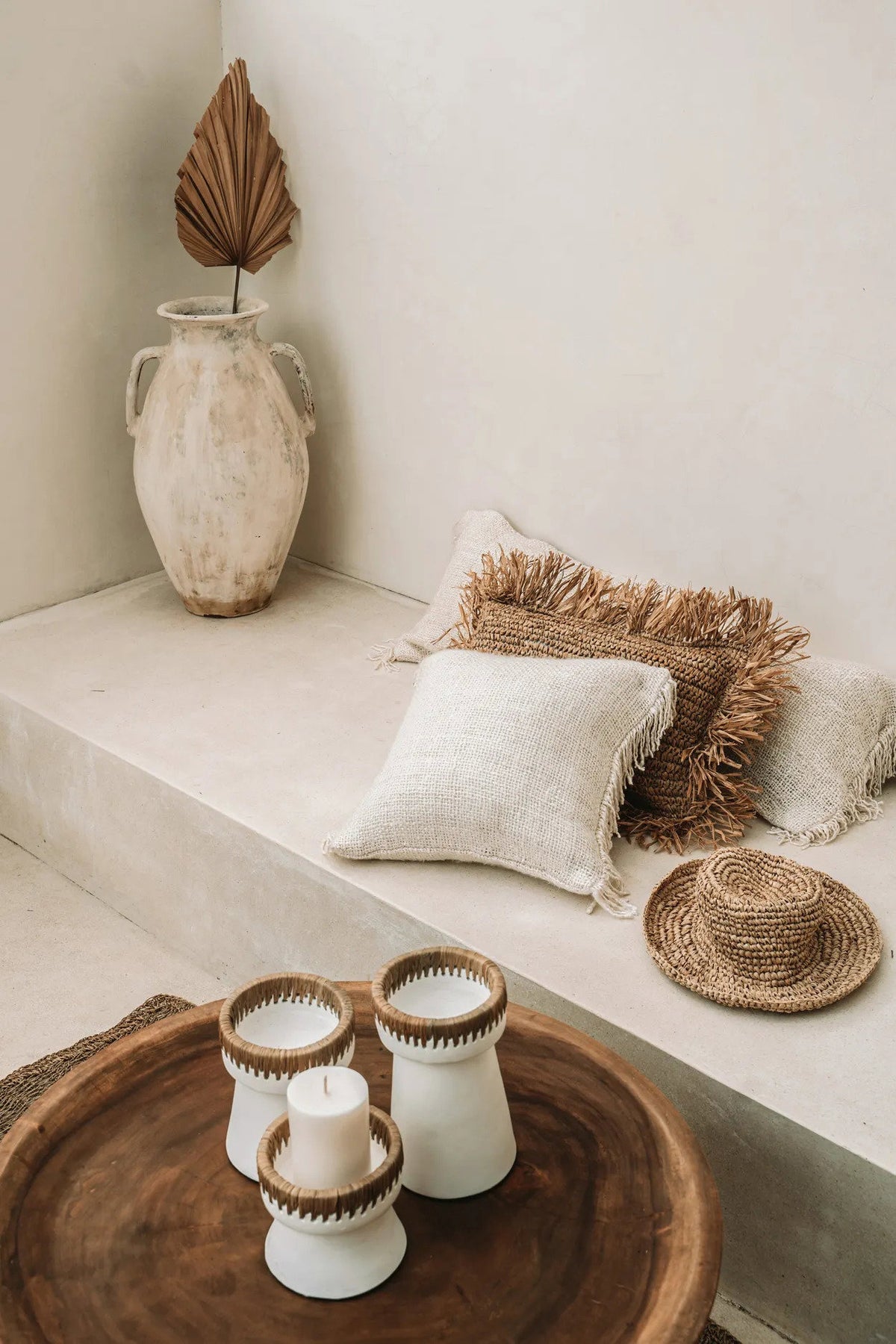 Lime wash plastered room with raffia and wood accessories and cream cushions