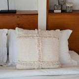 Decorative pillow on a bed with a wooden headboard and shelves in the background.