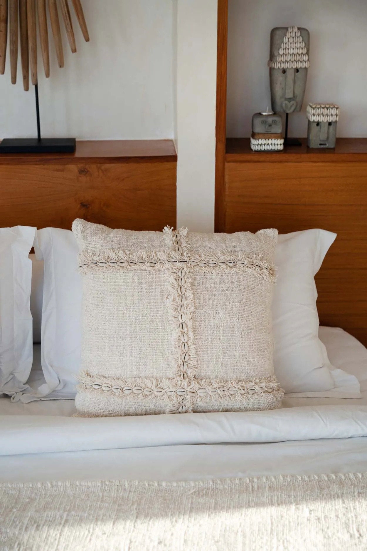 Decorative pillow on a bed with a wooden headboard and shelves in the background.