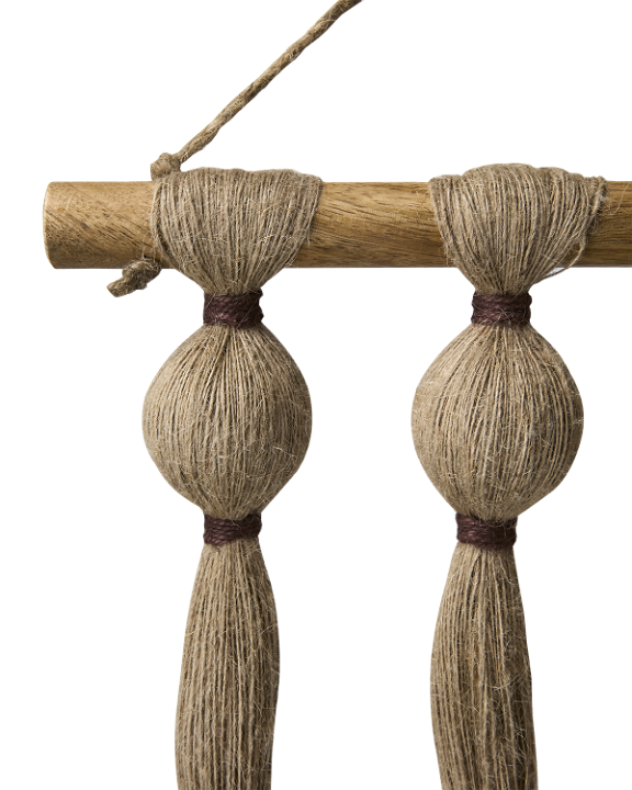 Close up of a wall hanging wooden pole and jute cotton strands