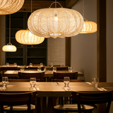 Dining area with extra large wicker rattan pendant lights and set tables.