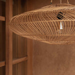 Woven rattan pendant light hanging against a warm-toned living room wall.