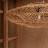 Woven rattan pendant light hanging against a warm-toned living room wall.