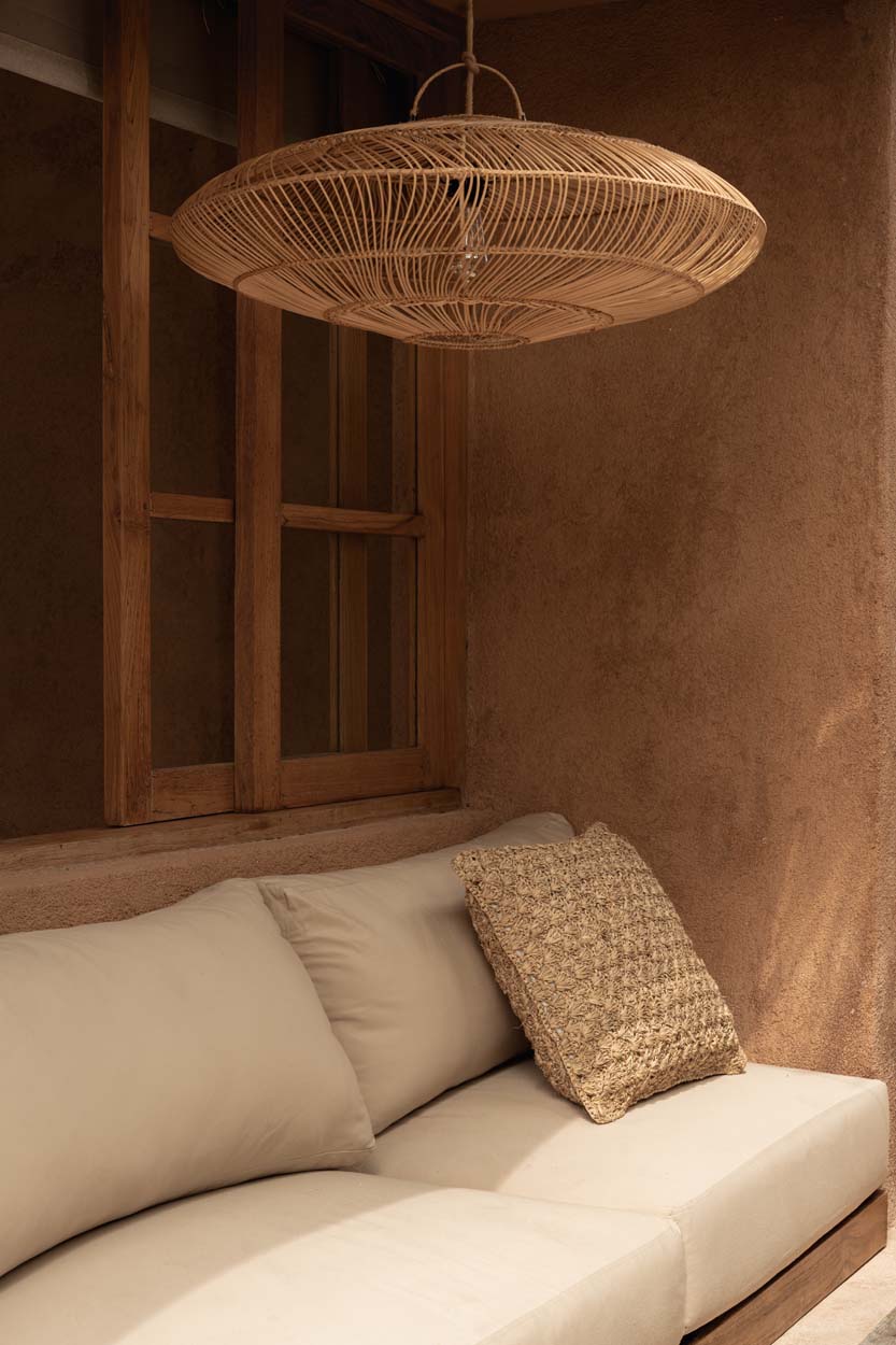 Beige sofa with textured pillow under a large wicker rattan pendant lime wash walls