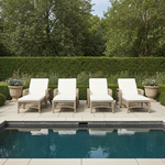 4 Cream cushioned rattan wicker sun loungers next to a pool on stone patio