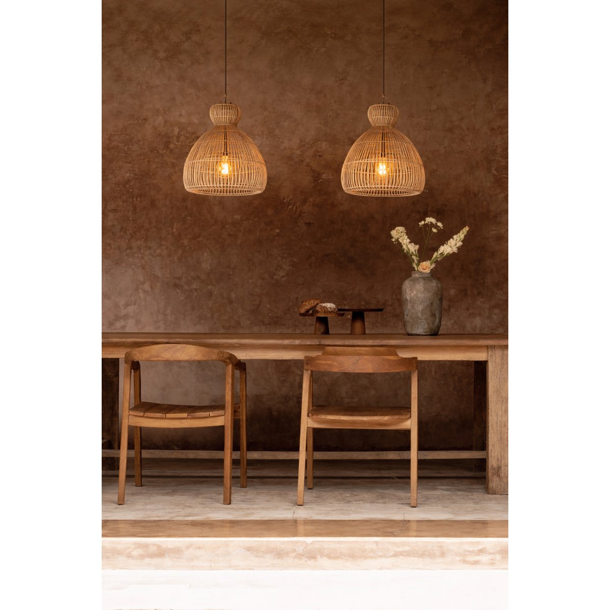 kitchen Dining area with wooden  table, chairs, and rattan pendant lights against a brown wall.