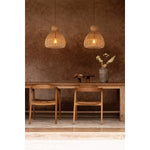 kitchen Dining area with wooden  table, chairs, and rattan pendant lights against a brown wall.