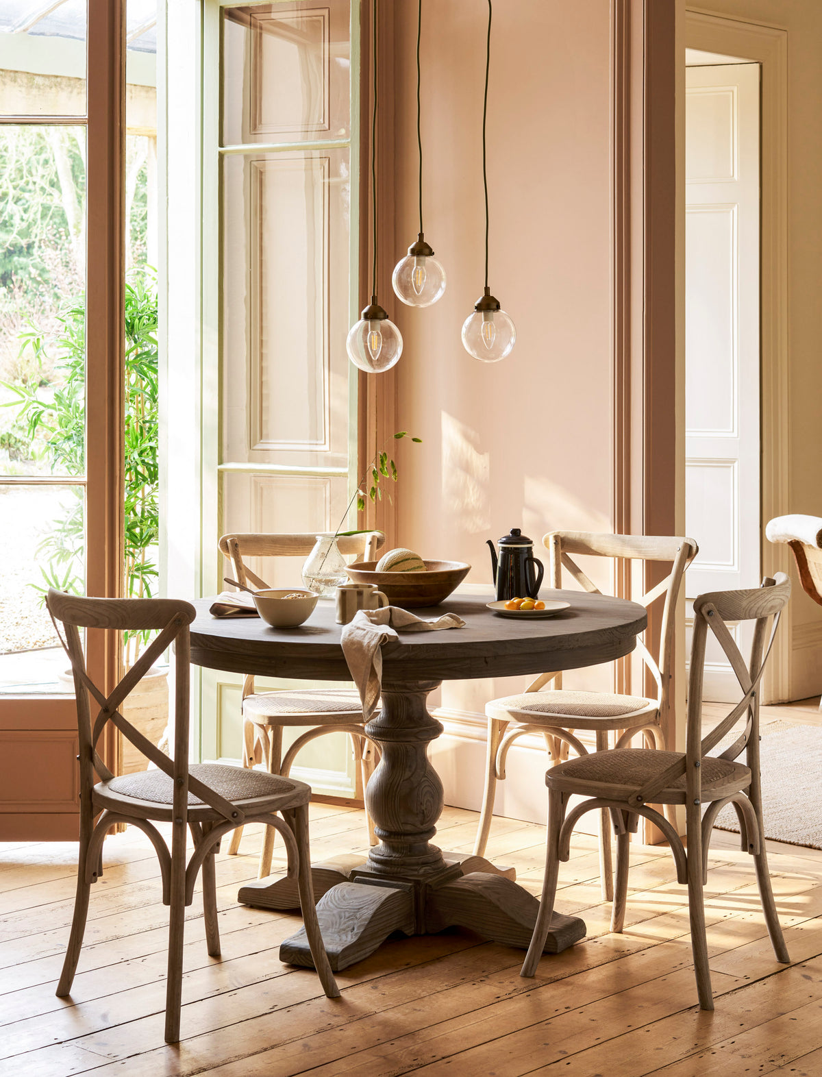 Garden dining area with a round wooden table and chairs in a well lit room.