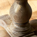 Close-up of a wooden pedestal with intricate carvings on a wooden surface.