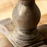 Close-up of a wooden pedestal with intricate carvings on a wooden surface.