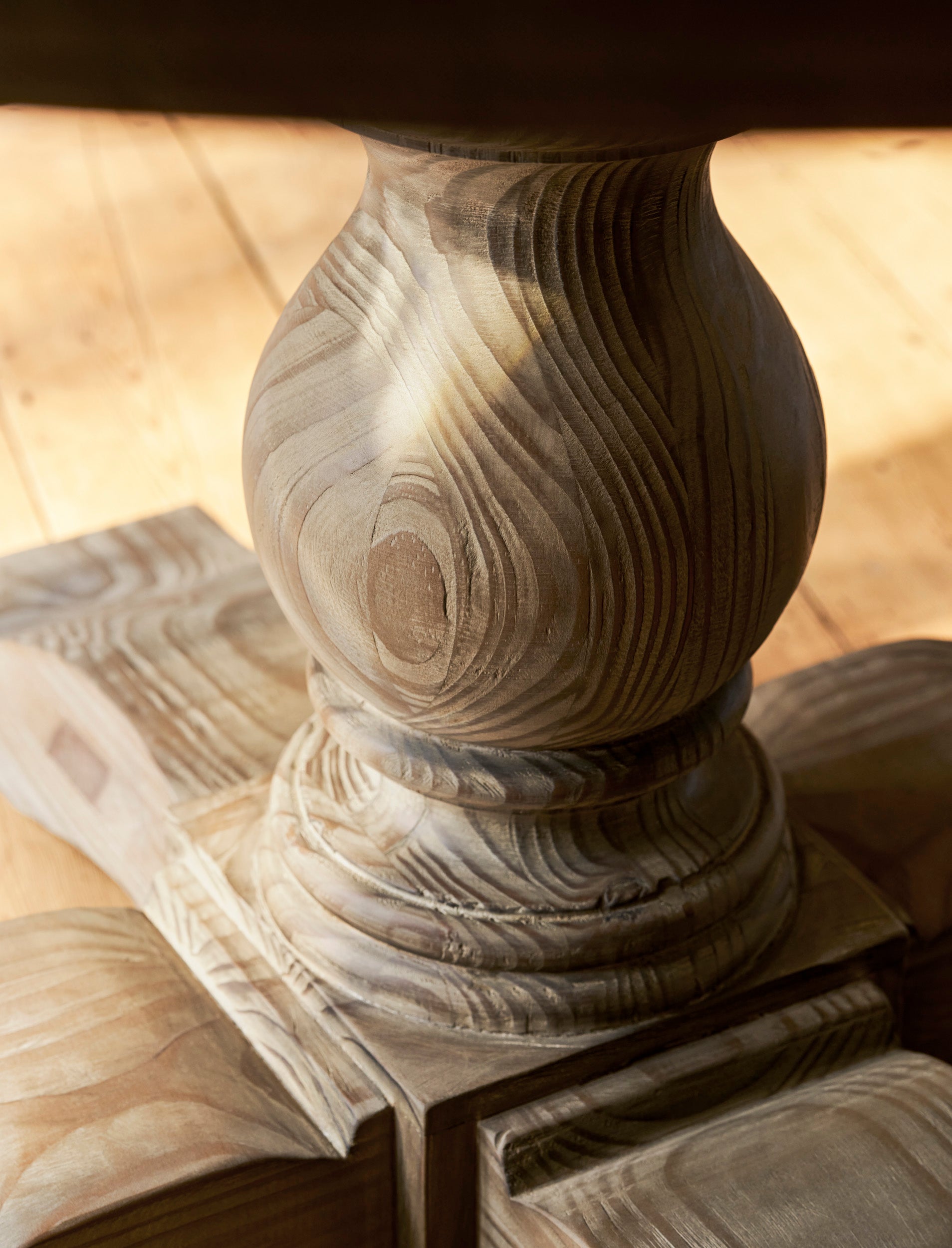 Close-up of a wooden pedestal with intricate carvings on a wooden surface.