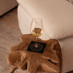 Wine glass on a wooden side table with a couch in the background