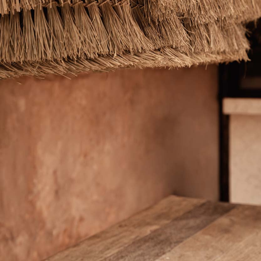 Close-up of a rattan and seagrass chandelier pendant light  and wooden table in a rustic setting