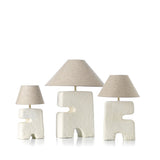 Three unique table lamps with geometric designs on a white background