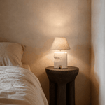 Bedside , space saving small Lamp on a wooden side table next to a bed in a softly lit room
