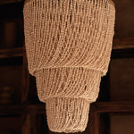 Textured shell chandelier pendant light hanging against a blurred background
