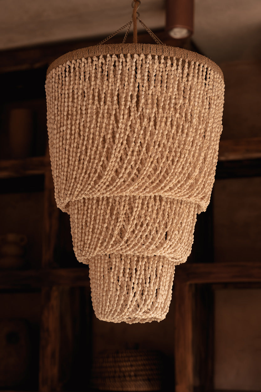 Textured shell chandelier pendant light hanging against a blurred background