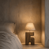 Bedroom with a textured wall, bed, and wooden lamp.
