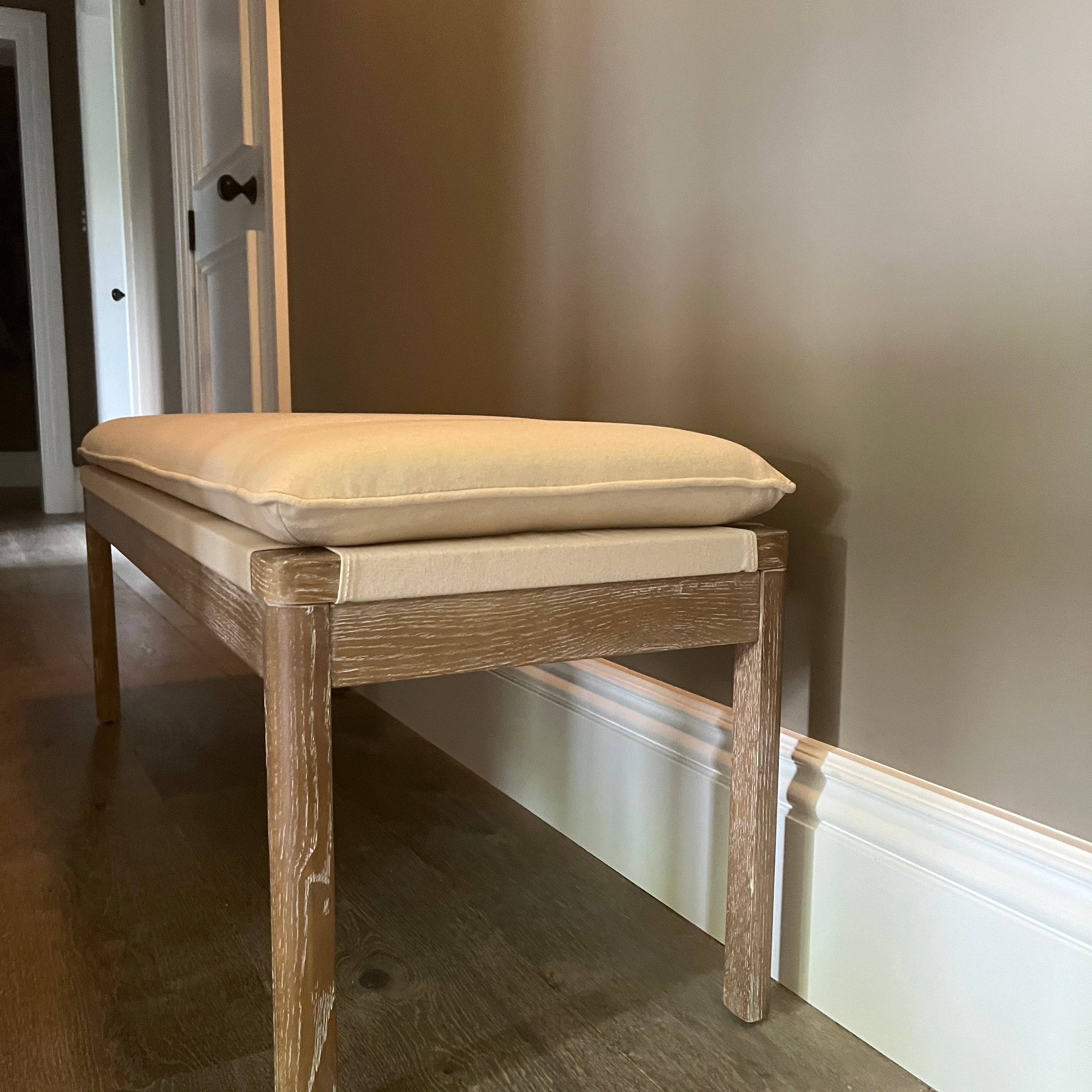 Upholstered wooden bench with cream padded cushion
