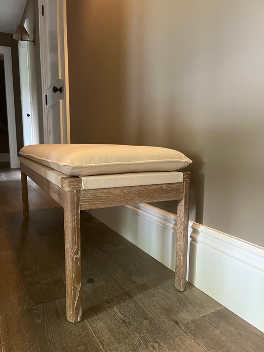 Upholstered wooden bench with cream padded cushion