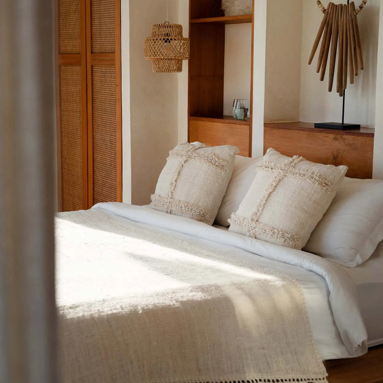 Bedroom with wooden shelves, natural cushions, rattan light, crochet bedspread