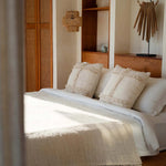 Bedroom with wooden shelves, natural cushions, rattan light, crochet bedspread
