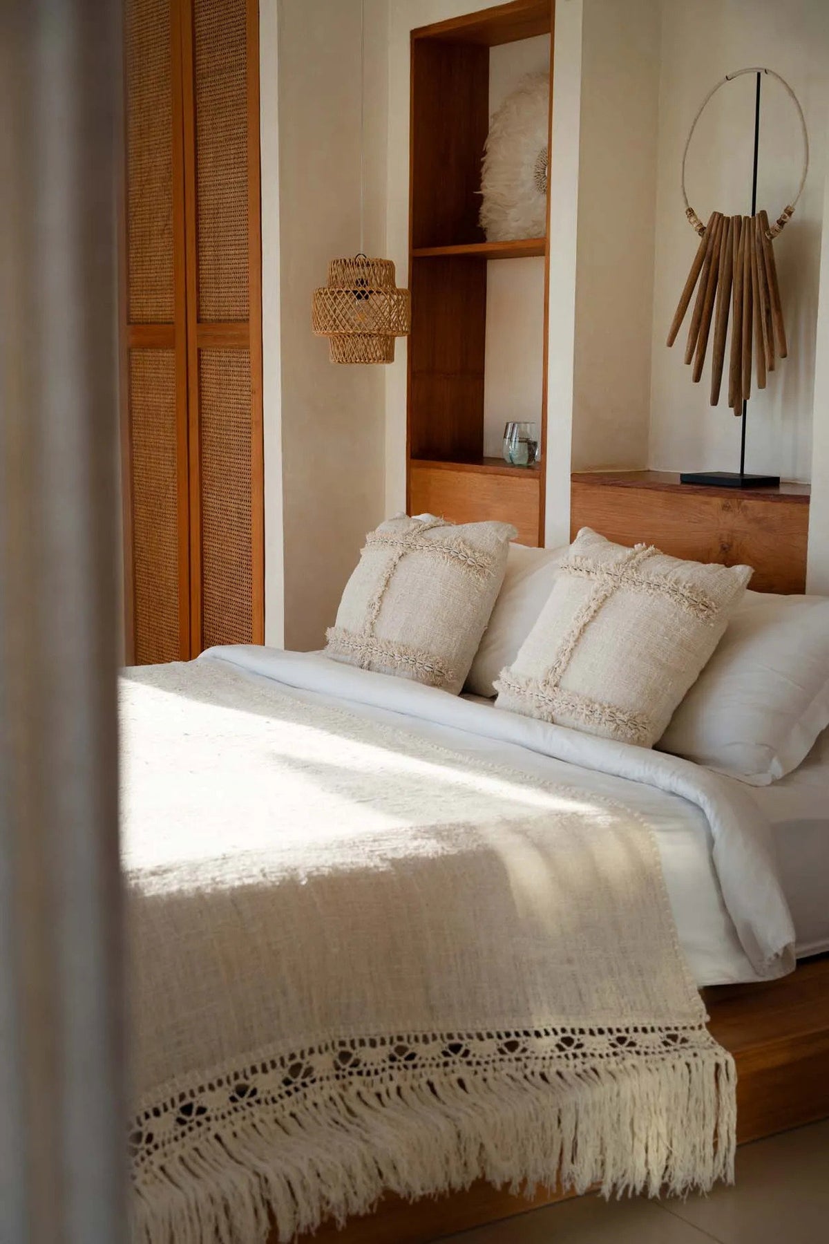 Bedroom with wooden shelves, natural cushions, rattan light, crochet bedspread