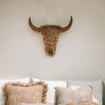 Decorative pillows on a sofa with a bull head sculpture on the wall.