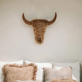 Decorative pillows on a sofa with a bull head sculpture on the wall.