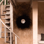 Staircase leading to a room with a decorative black grass large mirror on the wall.