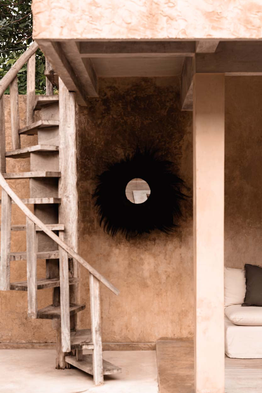 Staircase leading to a room with a decorative black grass large mirror on the wall.