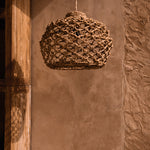 Woven pendant light hanging against a textured wall.