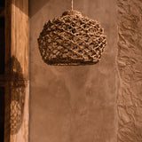 Woven pendant light hanging against a textured wall.