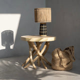Wooden side table with a woven lamp and bag against a gray wall
