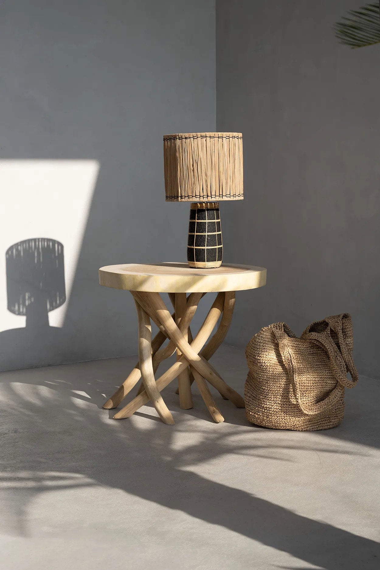 Wooden side table with a woven lamp and bag against a gray wall