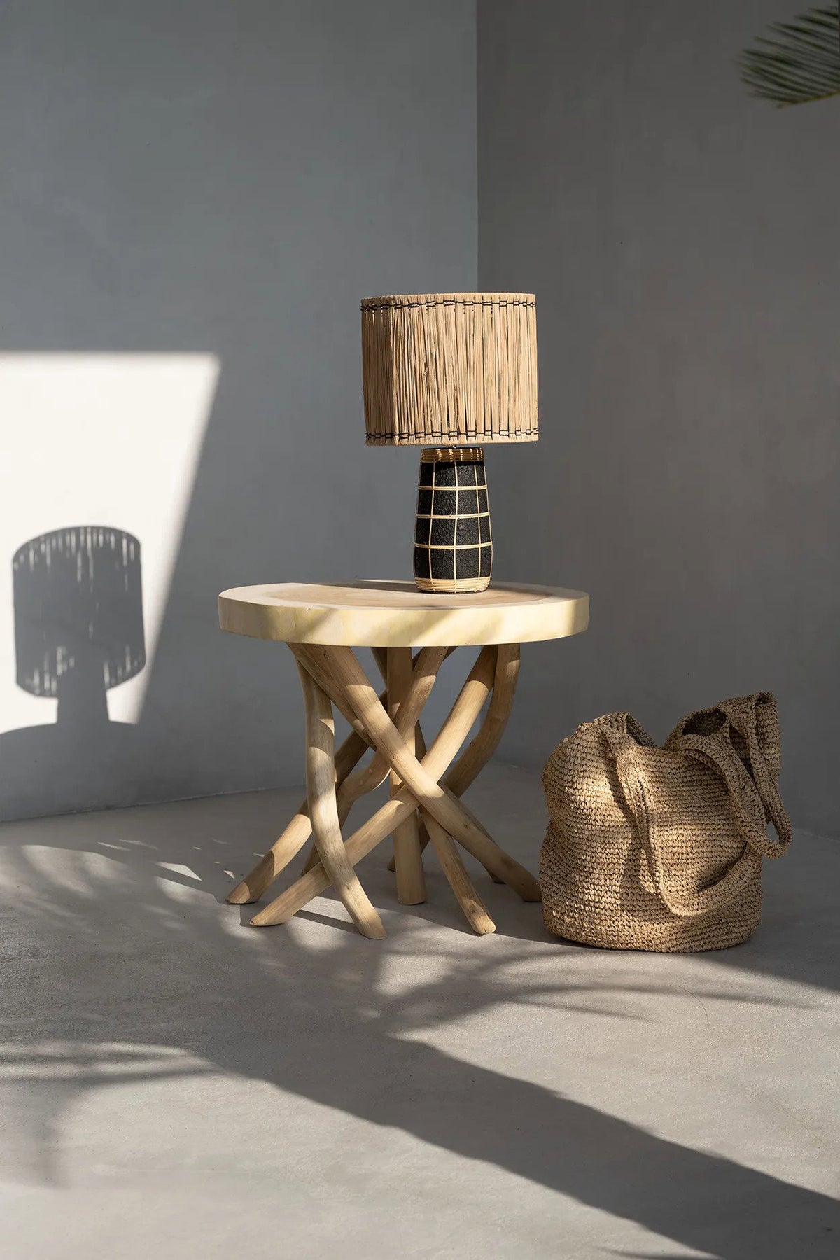 Wooden side table with a woven lamp and bag against a gray wall